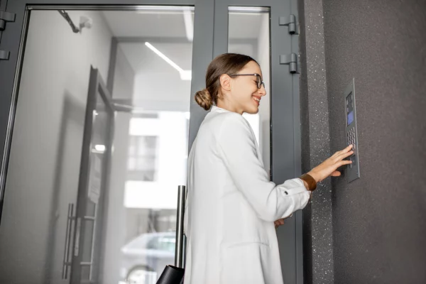 Young business woman in white suit entering code on the intercom system for business